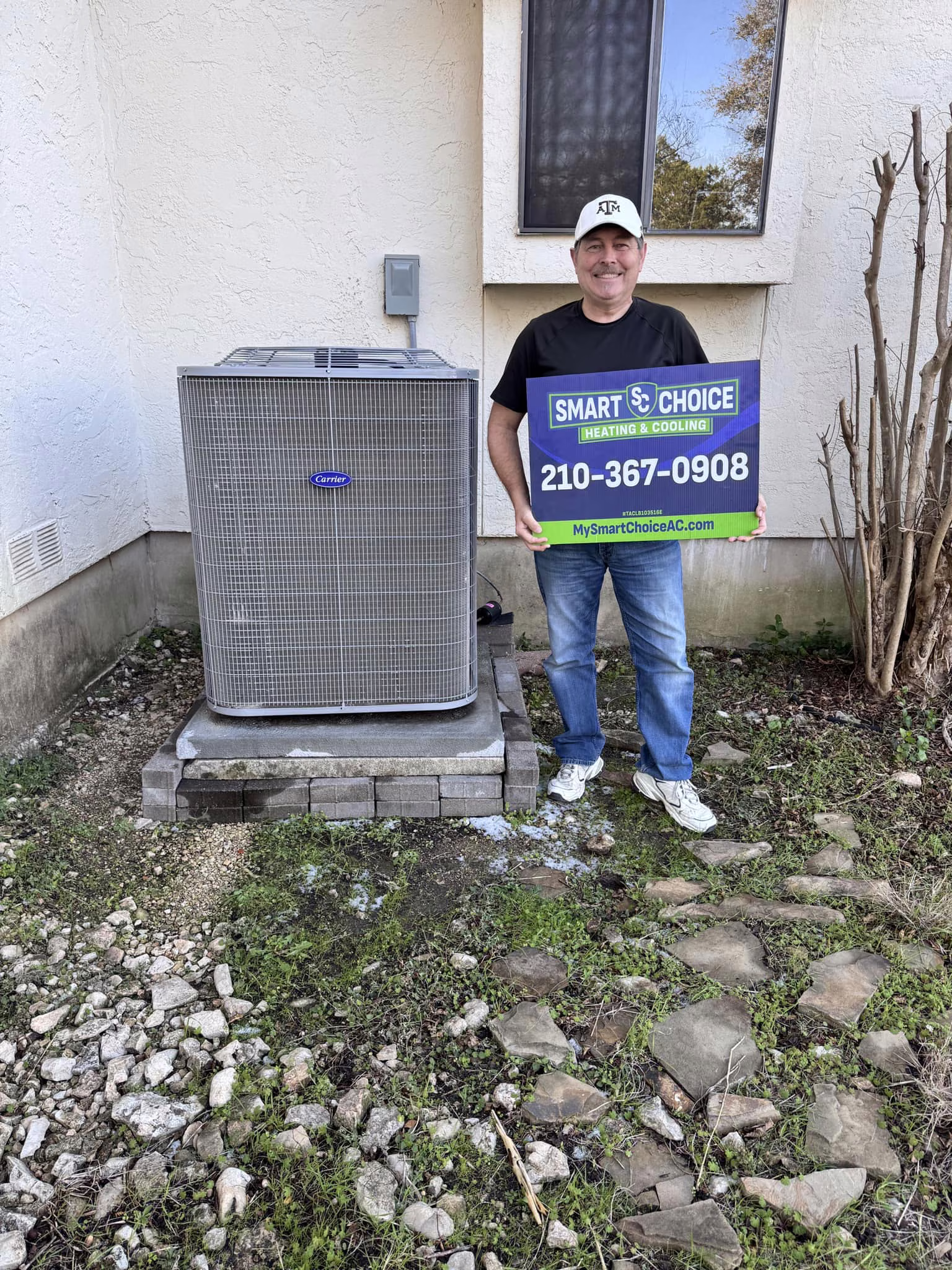 San Antonio homeowner holding a Smart Choice Heating and Cooling sign beside his new outdoor AC condenser